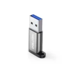 Adaptador USB-C Hembra a USB-A 3.0 Macho Delcom: ¡Conecta tus Cables USB-C en Cualquier Puerto USB!, Pequeño adaptador Delcom DOTG-USB3.0 de color plateado, mostrando el conector USB-A macho y el puerto USB-C hembra, con su cordón de seguridad de nylon, producto de HD Multimedia.